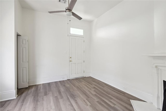 unfurnished living room with ceiling fan, a fireplace, wood finished floors, and baseboards