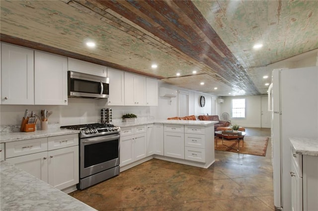 kitchen with appliances with stainless steel finishes, light stone counters, white cabinetry, and a wall mounted air conditioner