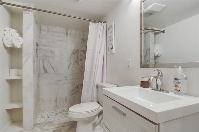 full bath with a tile shower, vanity, and toilet