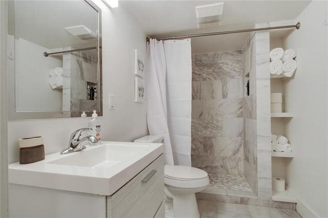 bathroom featuring a tile shower, vanity, and toilet