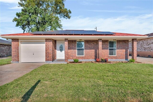 single story home featuring a front lawn, solar panels, and a garage