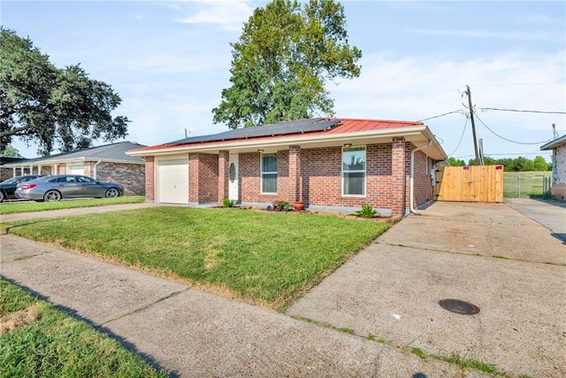 single story home with solar panels, a front yard, and a garage