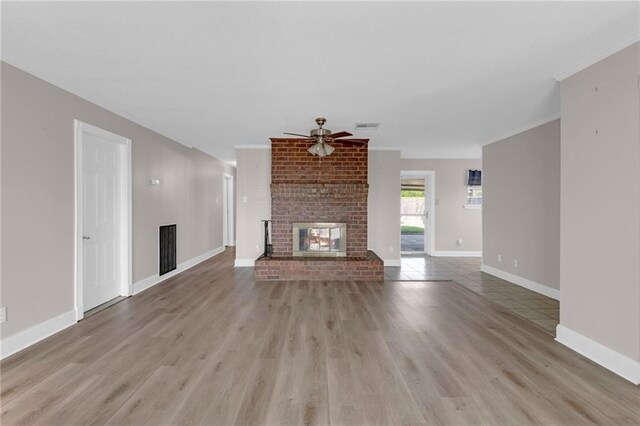 unfurnished living room with ceiling fan, a fireplace, hardwood / wood-style flooring, and brick wall