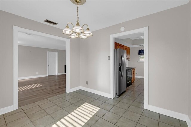 unfurnished room with light tile patterned floors and an inviting chandelier