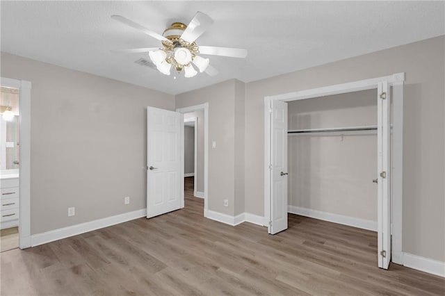 unfurnished bedroom featuring ceiling fan, ensuite bathroom, a closet, and light hardwood / wood-style flooring