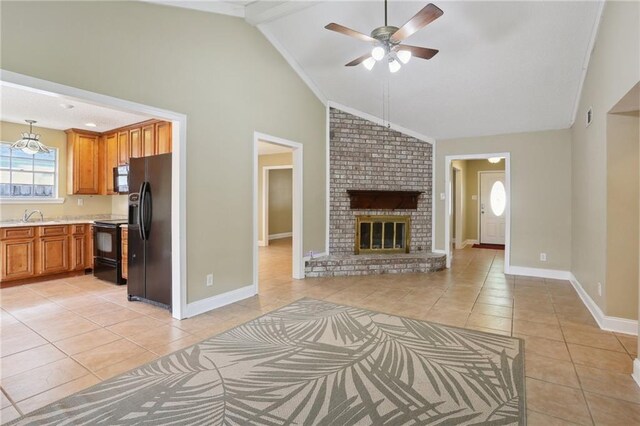 unfurnished living room featuring a brick fireplace, vaulted ceiling, ceiling fan, light tile patterned flooring, and sink