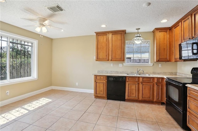 kitchen with a wealth of natural light, pendant lighting, sink, light tile patterned floors, and black appliances