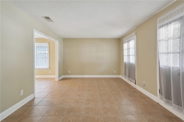 tiled empty room featuring a textured ceiling