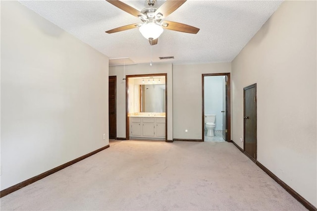 unfurnished bedroom with ceiling fan, ensuite bath, light colored carpet, and a textured ceiling