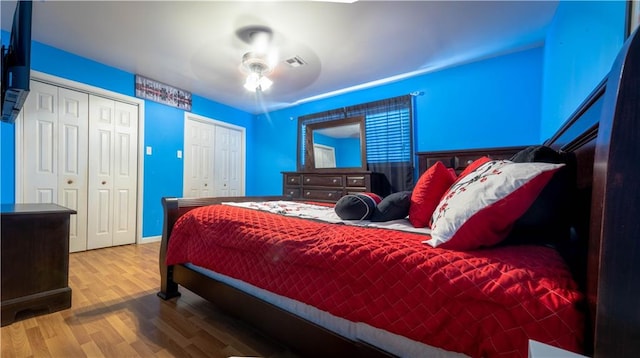 bedroom with ceiling fan, two closets, and hardwood / wood-style flooring