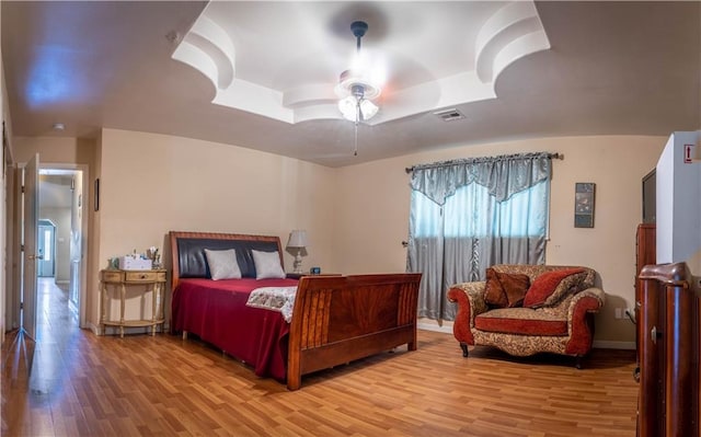 bedroom featuring hardwood / wood-style floors, ceiling fan, and a raised ceiling