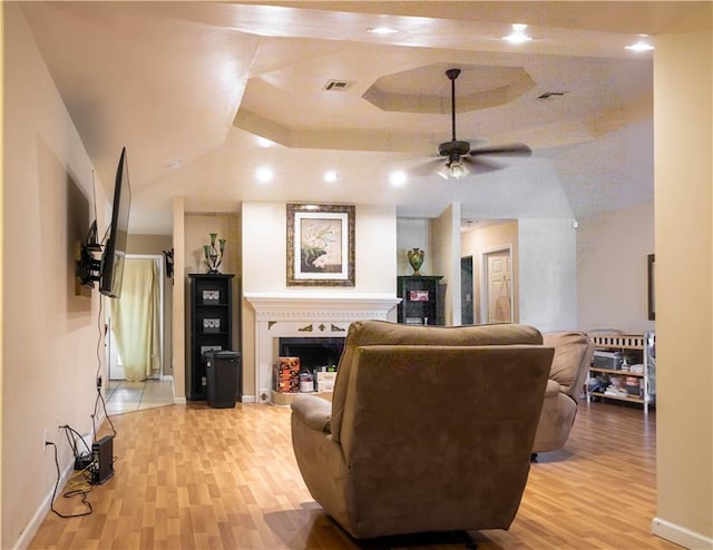 living room featuring ceiling fan, a raised ceiling, and light hardwood / wood-style floors