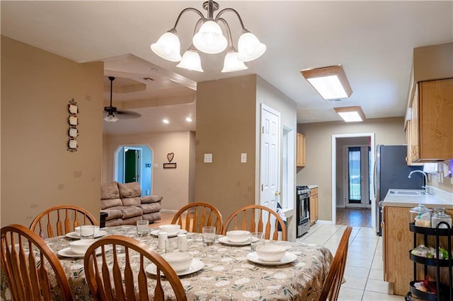 dining space with sink, ceiling fan with notable chandelier, and light hardwood / wood-style floors