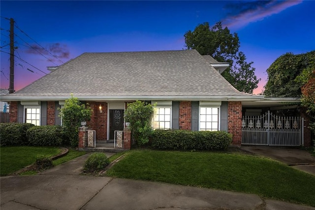 view of front of home featuring a front lawn, a shingled roof, and brick siding