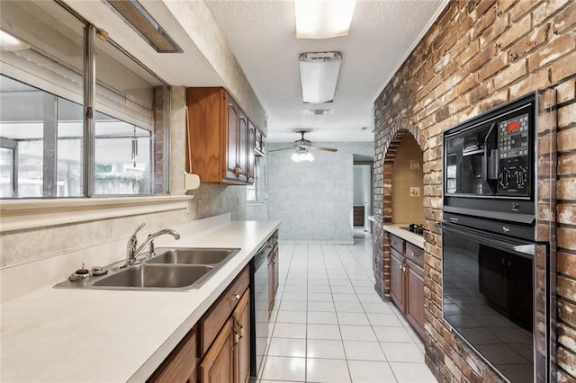 kitchen with light tile patterned floors, ceiling fan, sink, black appliances, and brick wall