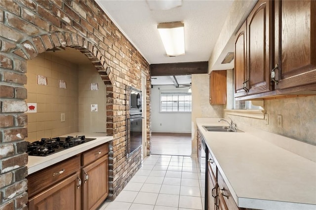 kitchen featuring beam ceiling, brick wall, sink, and black appliances