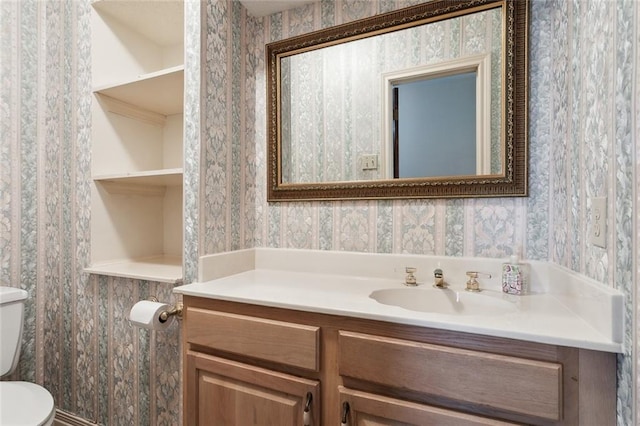 bathroom featuring vanity, built in shelves, and toilet