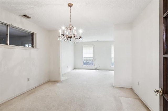 unfurnished room featuring a notable chandelier, a textured ceiling, and light colored carpet