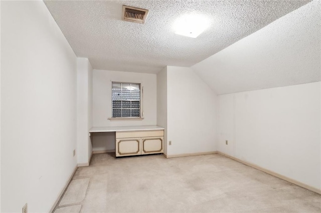 bonus room featuring a textured ceiling, lofted ceiling, and light carpet