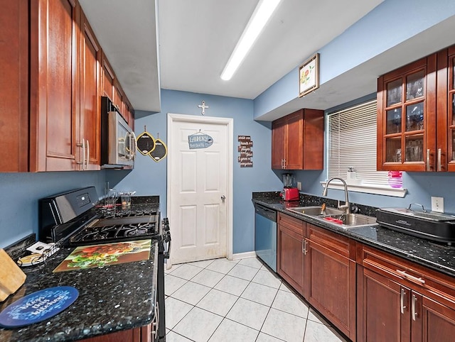 kitchen with light tile patterned floors, appliances with stainless steel finishes, dark stone countertops, and sink