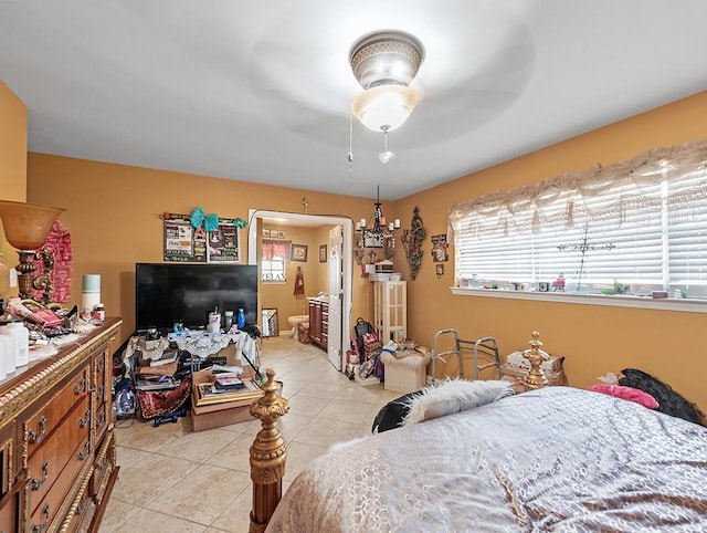 bedroom featuring ensuite bath, light tile patterned floors, and ceiling fan