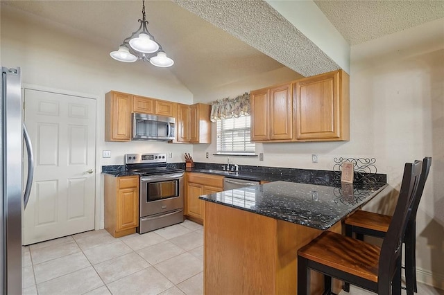 kitchen with a breakfast bar, light tile patterned flooring, stainless steel appliances, dark stone counters, and kitchen peninsula