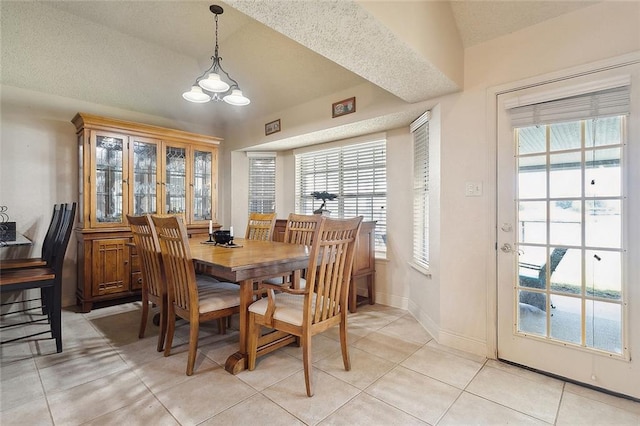 dining room featuring lofted ceiling, a textured ceiling, and light tile patterned floors