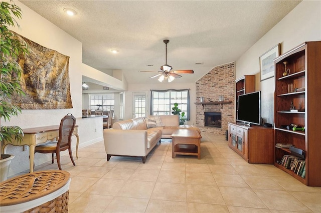 tiled living room featuring a textured ceiling, lofted ceiling, ceiling fan, brick wall, and a fireplace