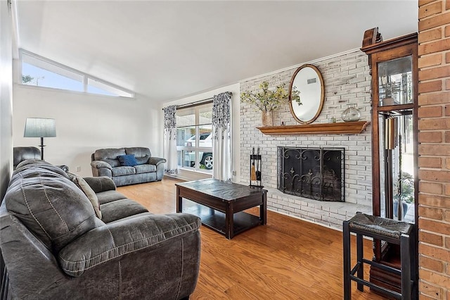 living room with hardwood / wood-style flooring, lofted ceiling, a wealth of natural light, and a brick fireplace