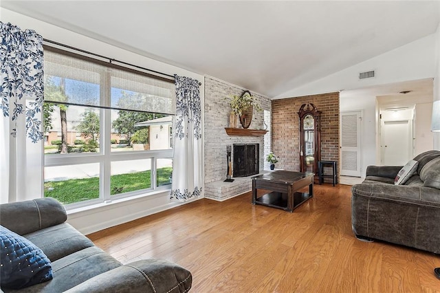 living room featuring hardwood / wood-style floors, a healthy amount of sunlight, a fireplace, and vaulted ceiling