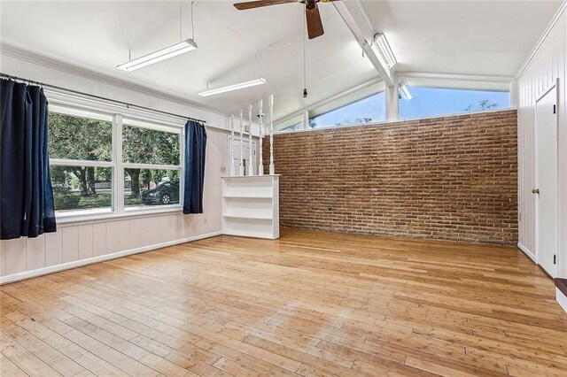 unfurnished living room featuring vaulted ceiling with beams, ceiling fan, light hardwood / wood-style flooring, and brick wall