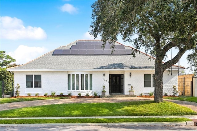 view of front of property featuring a front lawn and solar panels