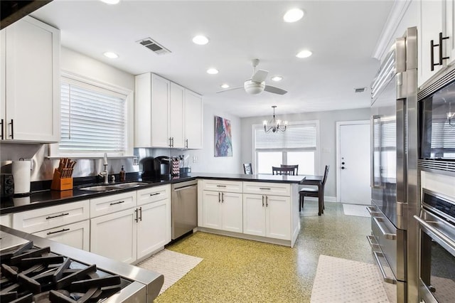 kitchen featuring white cabinetry, kitchen peninsula, appliances with stainless steel finishes, hanging light fixtures, and sink