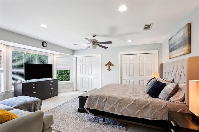 tiled bedroom featuring ceiling fan and two closets