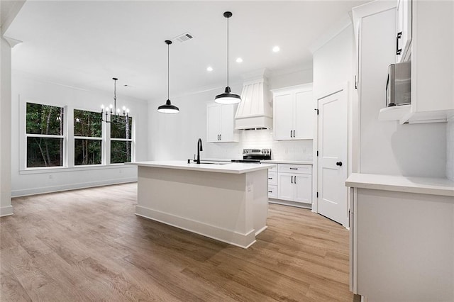 kitchen featuring premium range hood, sink, light hardwood / wood-style flooring, white cabinets, and an island with sink