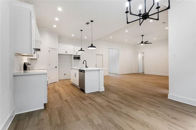 kitchen with hanging light fixtures, stainless steel appliances, an island with sink, white cabinets, and ceiling fan with notable chandelier