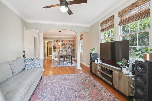 living room with decorative columns, ceiling fan, ornamental molding, and light hardwood / wood-style floors