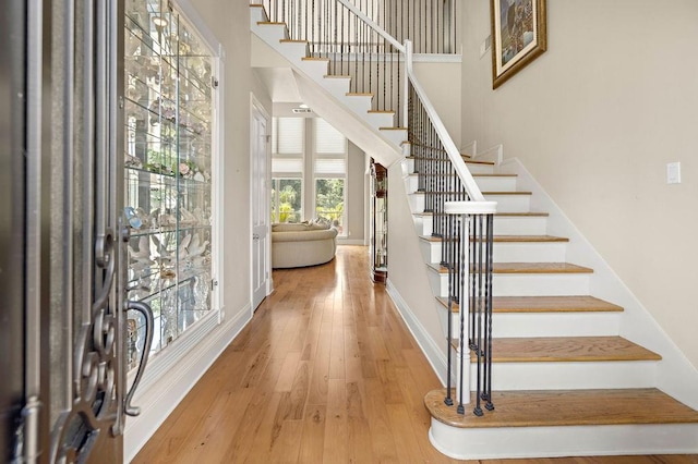 entryway featuring stairs, baseboards, hardwood / wood-style floors, and a towering ceiling