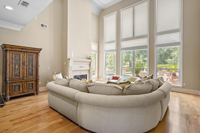 living room with high vaulted ceiling, ornamental molding, and light wood-type flooring