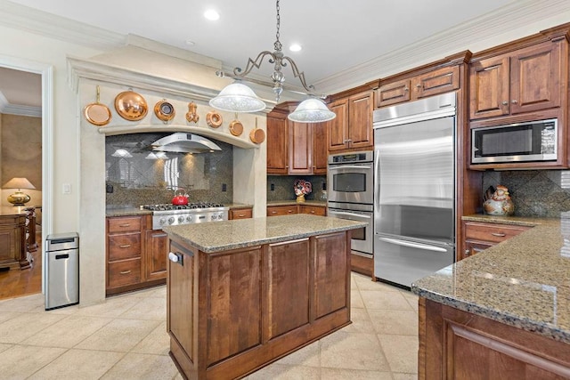 kitchen featuring built in appliances, backsplash, pendant lighting, and a kitchen island