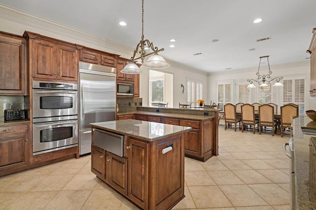 kitchen featuring decorative backsplash, built in appliances, pendant lighting, light tile patterned floors, and a center island