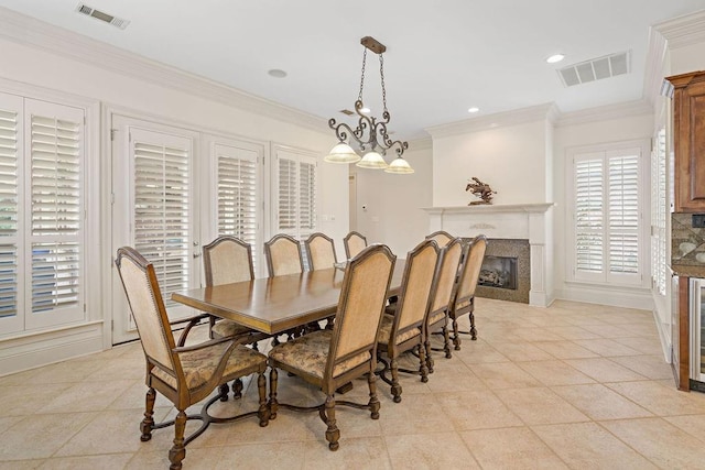 dining area with crown molding, light tile patterned flooring, a fireplace, and visible vents