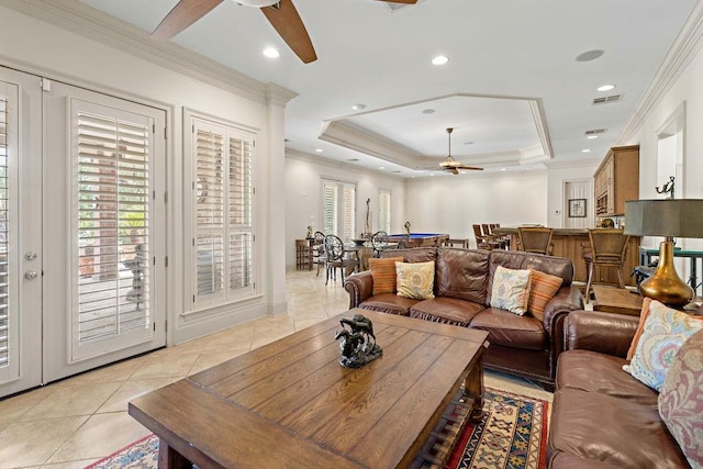 living room featuring ceiling fan, a raised ceiling, crown molding, and light tile patterned flooring