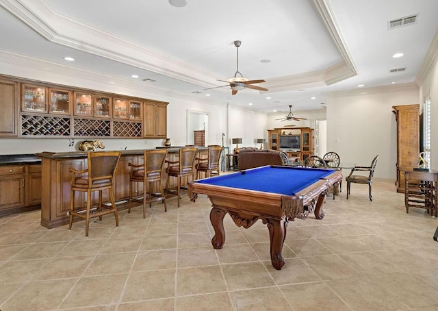 recreation room featuring indoor wet bar, a tray ceiling, light tile patterned floors, and visible vents