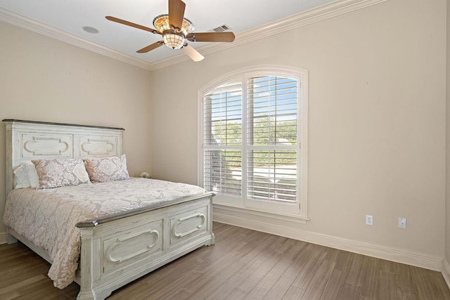 bedroom featuring visible vents, crown molding, ceiling fan, baseboards, and wood finished floors