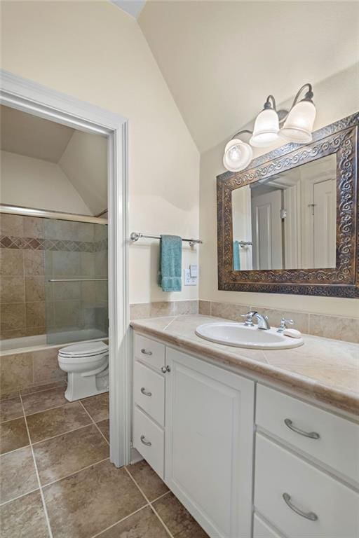 full bath featuring vanity, lofted ceiling, tile patterned flooring, tiled shower / bath combo, and toilet