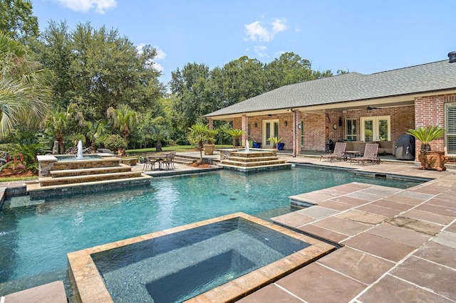 view of swimming pool with french doors, a pool with connected hot tub, a ceiling fan, and a patio area