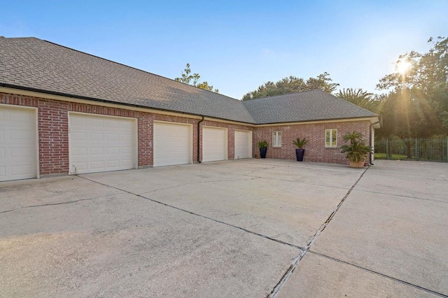 view of front of home featuring brick siding, concrete driveway, roof with shingles, and fence