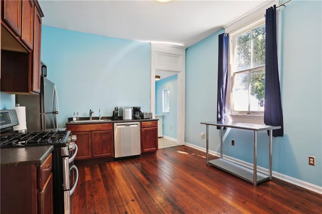 kitchen with appliances with stainless steel finishes, sink, and dark hardwood / wood-style flooring