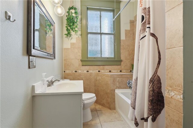 full bathroom with tile walls, toilet, shower / tub combo, tile patterned floors, and vanity